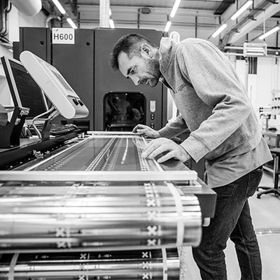 Black and white man in jacket operating CCL label press machine