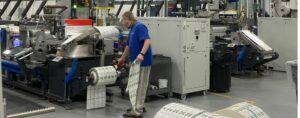 Man removing labels from factory printing machine