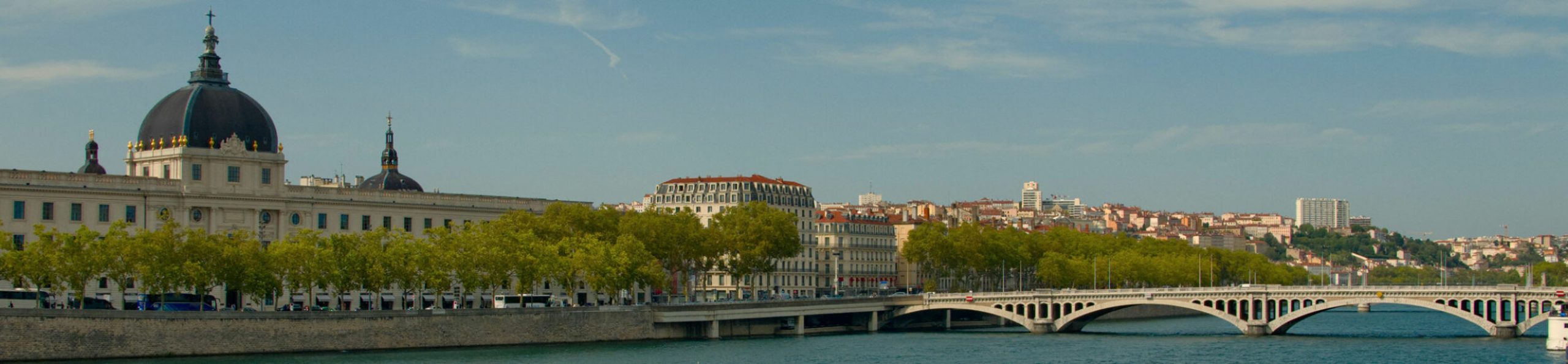 city of lyon by the water with a bridge and old buildings under a clear sky